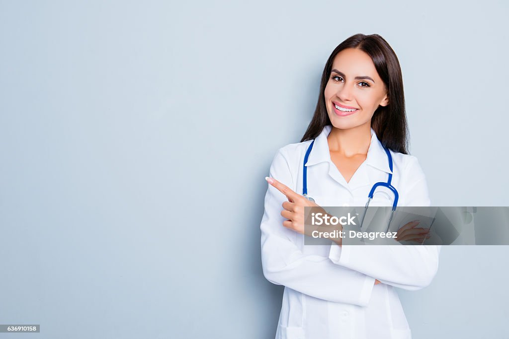 Smiling happy doctor pointing with finger on blue background Doctor Stock Photo