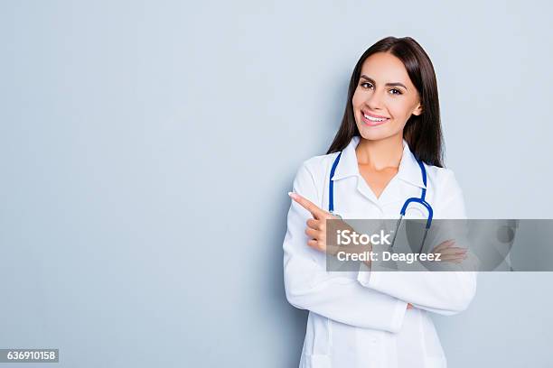 Smiling Happy Doctor Pointing With Finger On Blue Background Stock Photo - Download Image Now