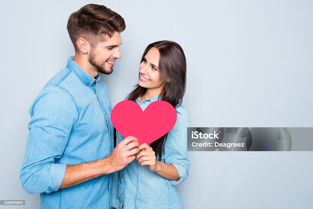 Two lovers holding paper heart on gray background Boyfriend Stock Photo