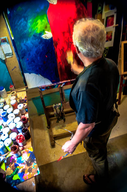 istock Elderly man with white hair, artist, painter, working.. 636910908