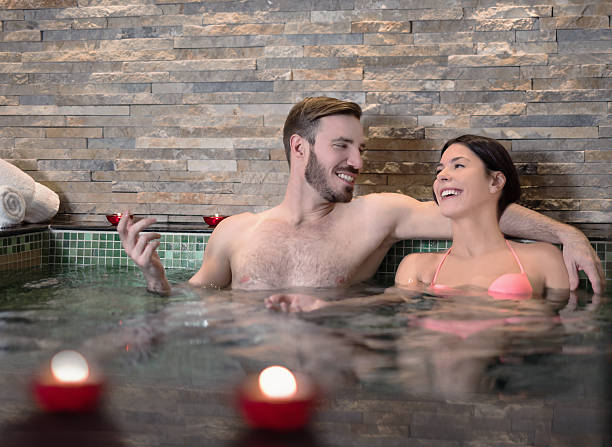 jovem casal na banheira quente falando e rindo - couple hot tub spa treatment health spa - fotografias e filmes do acervo