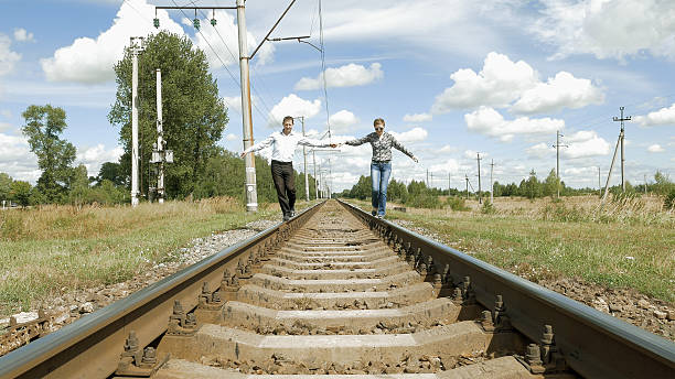 istock Man and woman holding hands walking along railway 636912380