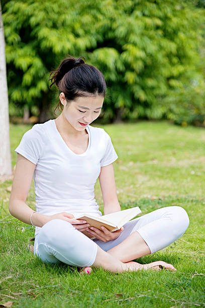 istock Young woman reading a book in park 636912806