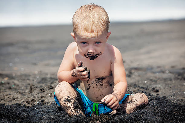 glücklich schmutziges kind spielen mit sand auf familie strandurlaub - people eating walking fun stock-fotos und bilder