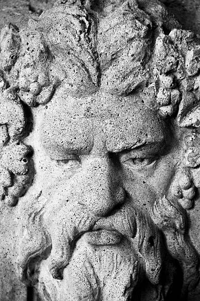 Architectural stone carving of a decorative face adorned with detailed features, captured in monochrome. The ornate design highlights artistic craftsmanship and lends historical charm to the facade