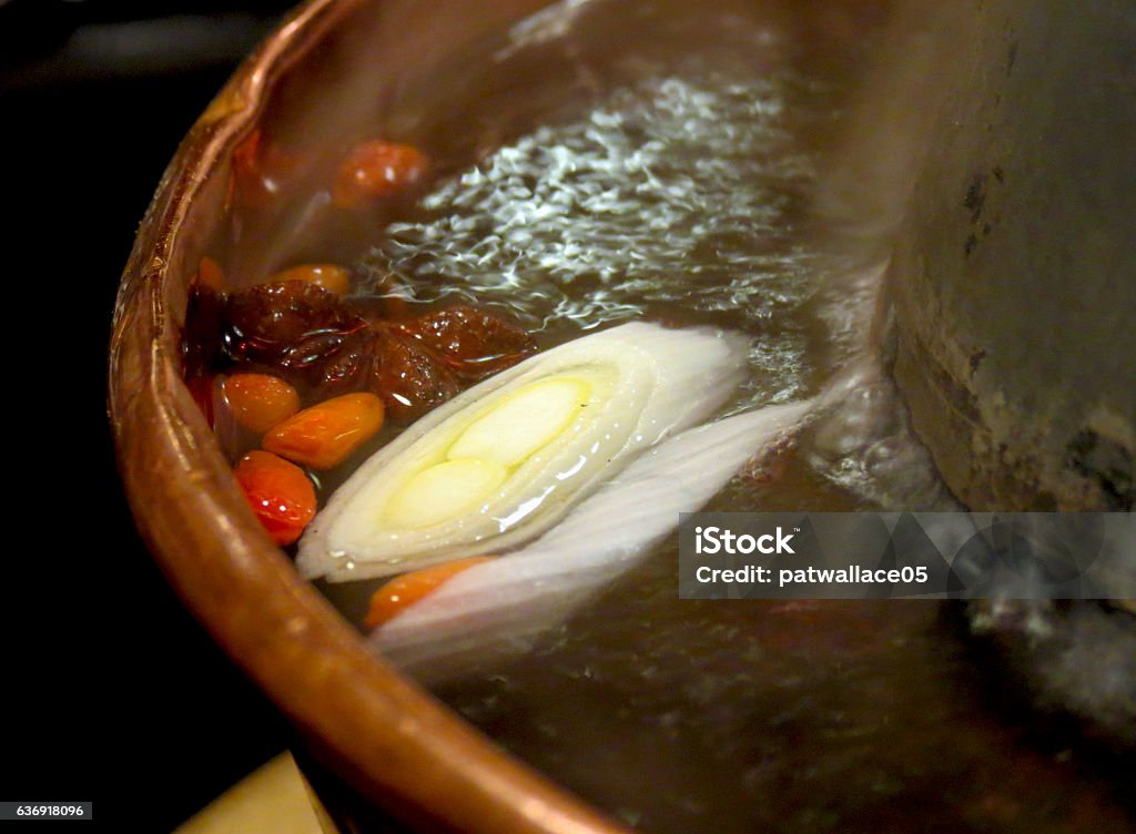 Detail of Chinese hotpot Close-up view of a Chinese hotpot, with leeks and wolfberries boiling in the broth. Asia Stock Photo