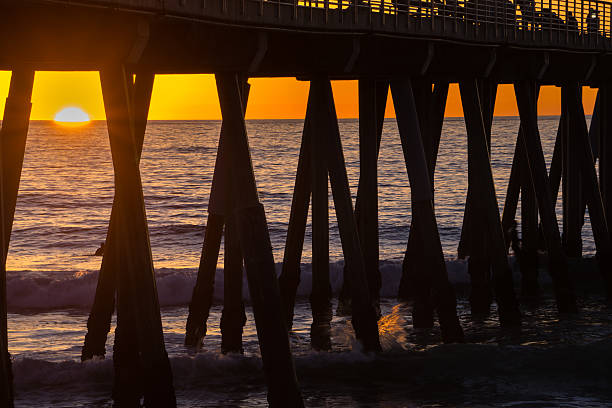 エルモサビーチ桟橋の下のサーファー - santa monica surfing beach city of los angeles ストックフォトと画像