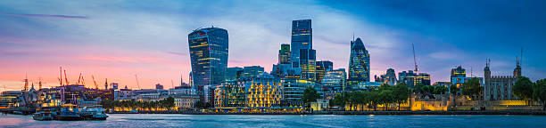 City of London skyscrapers illuminated at sunset overlooking Thames panorama Sweeping panoramic sunset across the River Thames at London Bridge, reflecting the illuminated skyscrapers of the City, the office buildings of the Embankment and the futuristic towers of the Walkie Talkie and the Cheesegrater in the heart of the UK's vibrant capital city. bankside photos stock pictures, royalty-free photos & images