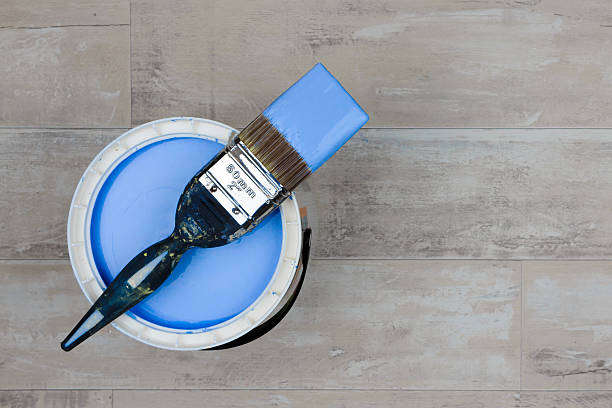 istock Loaded paintbrush across an open can of mid blue paint 636937254