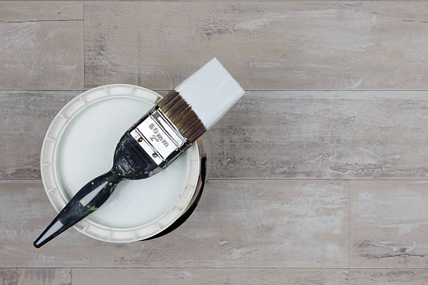 istock Loaded paintbrush across an open can of light grey paint 636937272