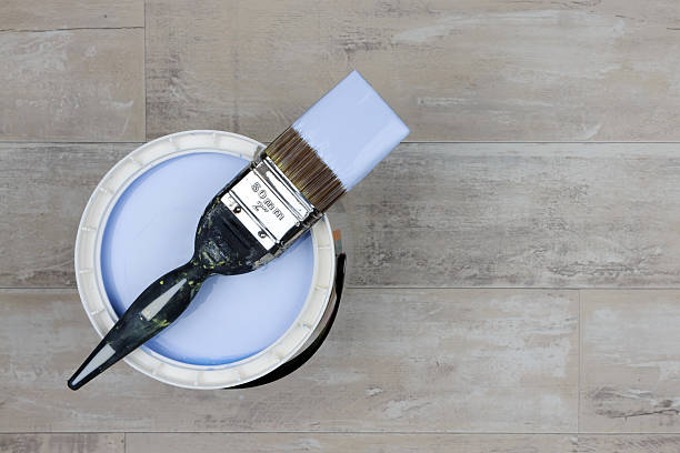 istock Loaded paintbrush across an open can of light blue paint 636937312