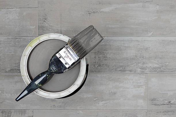 istock Loaded paintbrush across an open can of grey paint 636937326
