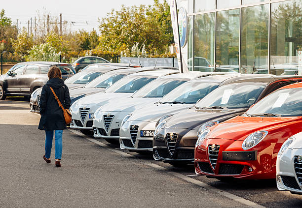 Shopping new car woman choosing car in a row Paris, France - October 10, 2015: Woman walking between rows of new car to choose the most precious one at the Alfa Romeo car store car finance stock pictures, royalty-free photos & images