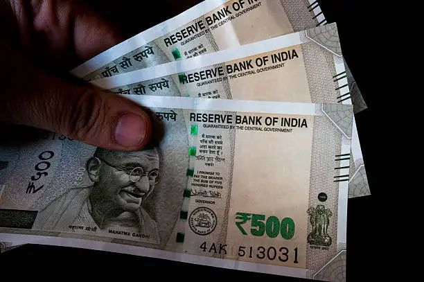 Person holding the new indian Rs 500 note isolated on black. These new currency notes have been recently authorized by the government