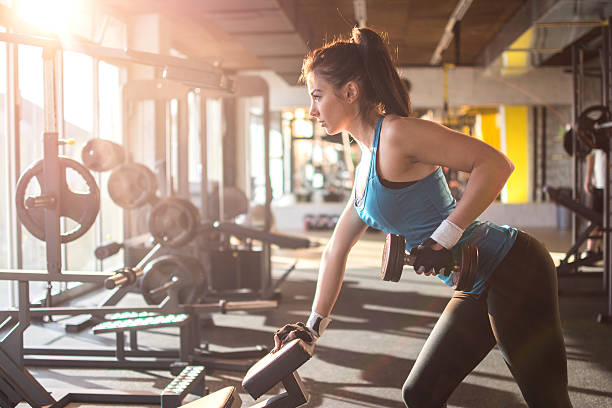 istock Sporty girl lifting weights in gym. 636947536