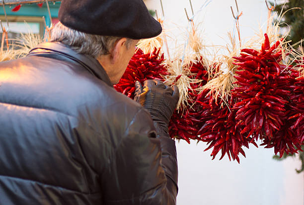 weihnachtsshopping: mann schaut auf chili-pepper weihnachtskränze - wreath chili pepper pepper ristra stock-fotos und bilder