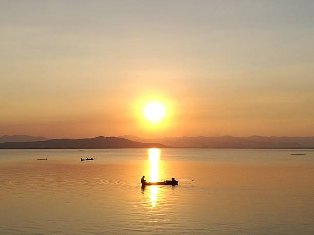 istock Silhouette sunset over lake having boat middle of sun reflection 636949952