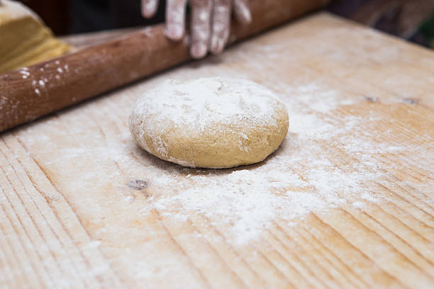 Woman hands kneading dough on kitchen table with rolling pin