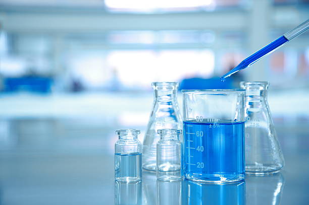 blauer tropfen in glasbecher mit kolben und wissenschaftslabor - laboratory glassware stock-fotos und bilder