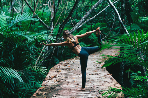 Young Caucasian woman doing yoga in the tropical forest