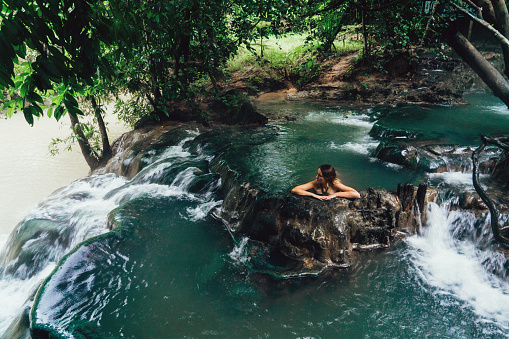 Young Caucasian woman bathing in hot spring waterfall in Thailand