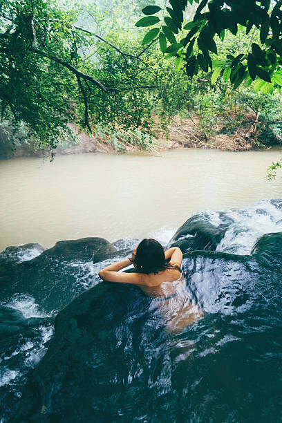 istock Woman bathing in hot spring waterfall 636966434