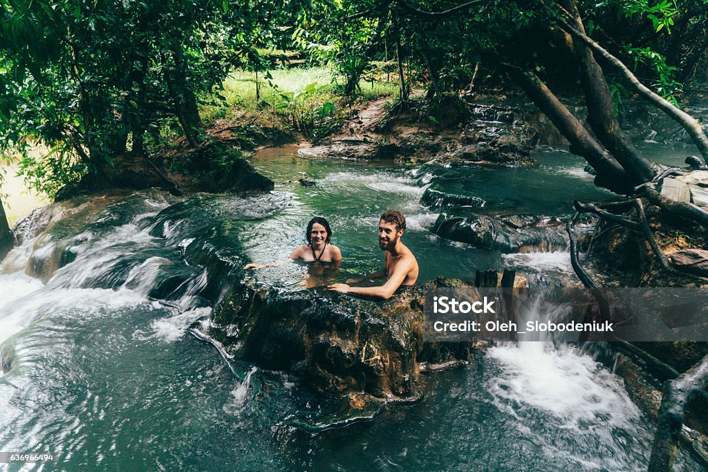 Couple bathing in hot spring waterfall Young Caucasian couple bathing in hot spring waterfall in Thailand Hot Spring Stock Photo
