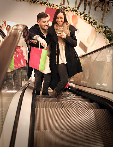 istock Smiling couple on escalator in shopping mall 636968772