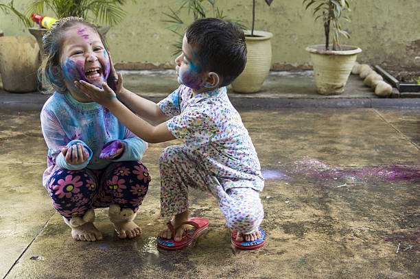 Kids Celebrating Holi Festival of Colors Two Indian kids with their face smeared with colors celebrate Holi, the festival of colors. mischief photos stock pictures, royalty-free photos & images