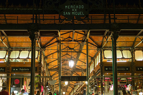 Madrid, Spain - September 10, 2016: Illuminated iron entrance to the Market of San Miguel in Madrid, Spain. Declared Bien de Interés Cultural in the year 2000, the building preserves its original iron structure from the beginning on the XX Century. It is located in the square of the same name, within walking distance from the Plaza Mayor.