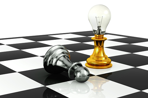 3D rendering of chess board with a silver pawn fallen down while a gold pawn with a light bulb as it's head standing next to it isolated on white background.