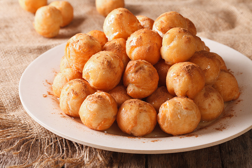 Turkish lokma donuts with honey and cinnamon close-up on a plate. horizontal