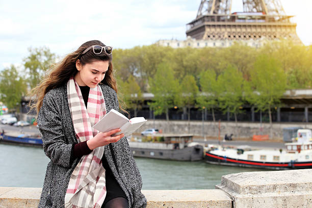 istock Woman reading book near Seine river 636985446