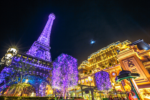 Macau, China - December 8, 2016: the spectacular blue and purple Macau Eiffel Tower, icon of The Parisian, a luxury Resort Hotel Casino in Cotai Strip owned by Las Vegas Sands, shines bright at night.