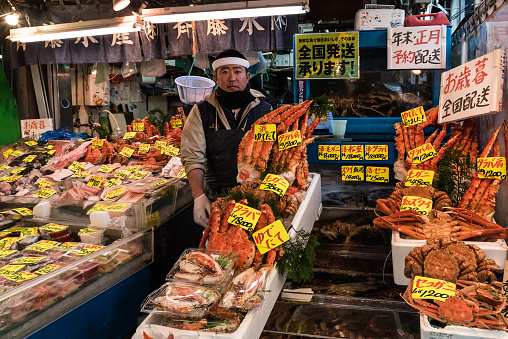 Tokyo, Japan - December 8, 2015: A Japanese man selling fresh king crab, fish & more seafood at Tsukiji Fish Market