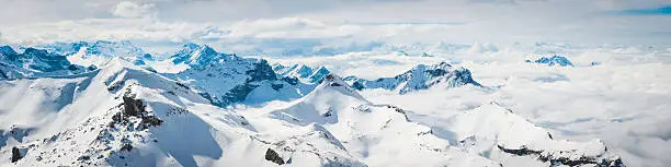 High altitude panoramic view across the crisp white glaciers, snow capped summits and dramatic rocky ridges of the Alps high in the idyllic mountain wilderness of the Bernese Oberland and Valais, Switzerland.