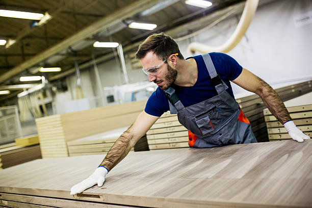 Jeune charpentier portant une planche de bois - Photo