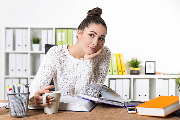 istock Dreamy office employee with books 636998514