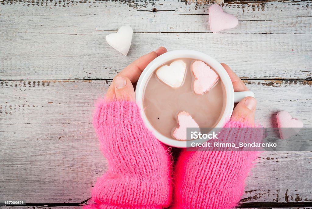 Girl drinking hot chocolate with marshmallows's hearts Girl drinking hot chocolate with marshmallows in the shape of hearts, Valentine's Day celebration, hands in the picture, top view, copy space Valentine's Day - Holiday Stock Photo