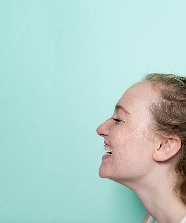 Profile image of laughing young woman by green background