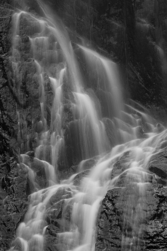 A long exposure photograph of a vail of water flowing the rocks of a waterfall