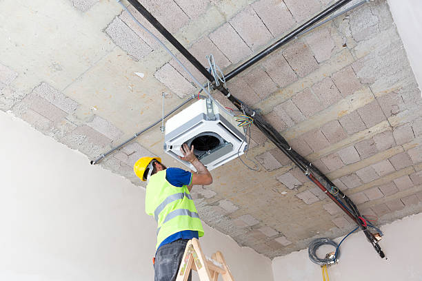 istock Electrician fitting air conditioning to office interior 637019274