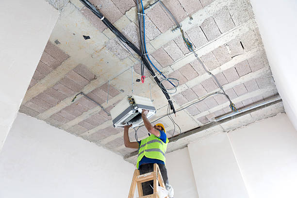 istock Electrician fitting air conditioning to office interior 637020892