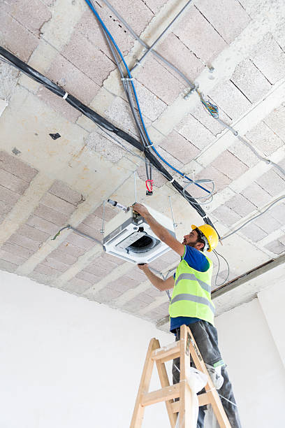 istock Electrician fitting air conditioning to office interior 637022072