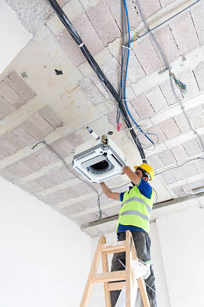 istock Electrician fitting air conditioning to office interior 637022364