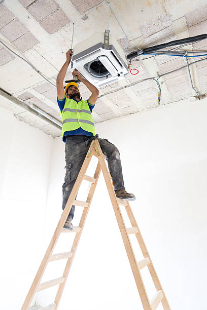 istock Electrician fitting air conditioning to office interior 637024370