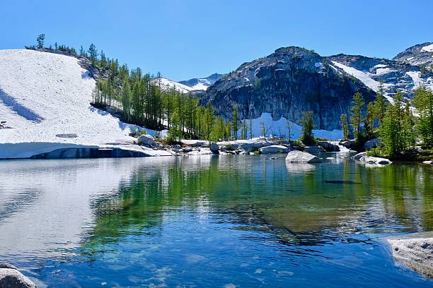 альпийское озеро, деревья и заснеженные скалы. - tree leavenworth snow sky стоковые фото и изображения