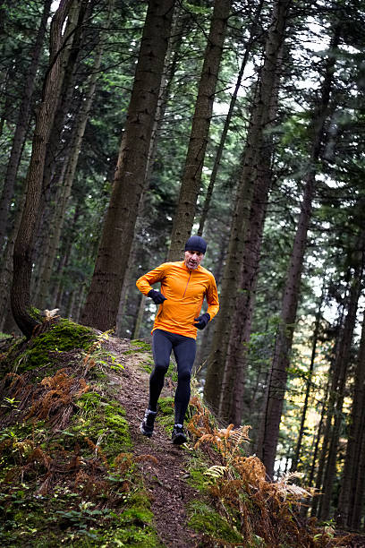 istock Athlete male runner running downhill in mountain autumn forest 637032222