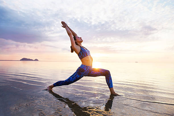 istock Young woman practicing yoga on the sunset beach 637033924