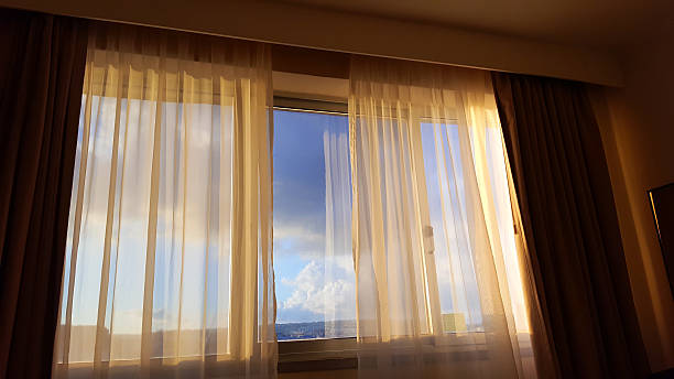 istock sunset behind curtain - open window view to sunset 637039826